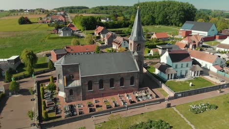 aerial shot of a church in flanders, belgium next to a small village in 4k