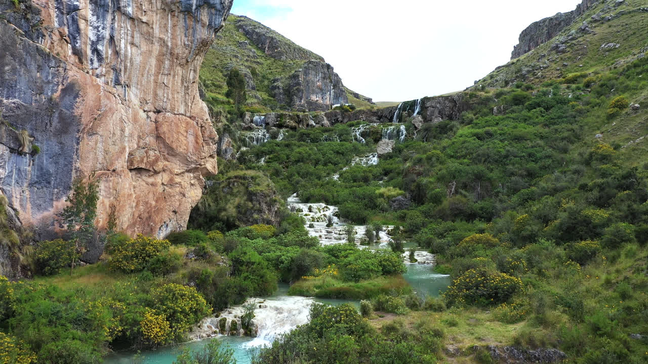 페루의 아야쿠초 (ayacucho) 에서 푸른 물을 가진 호수를 가로지르는 아름다운 드론 촬영은 늦은 오후에 식물이 있는 산의 한가운데에서 밀푸 (millpu) 라고 불립니다.