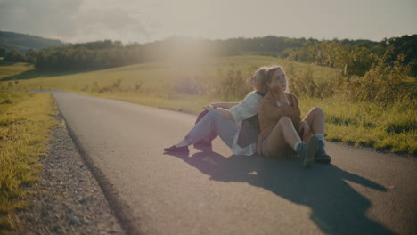 tired female friends resting on road meadow