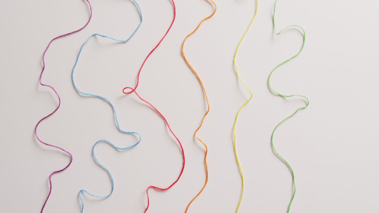 vídeo de seis bobinas de hilos de bordado de colores desenrollados sobre un fondo blanco