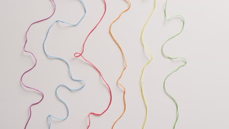 vídeo de seis bobinas de hilos de bordado de colores desenrollados sobre un fondo blanco