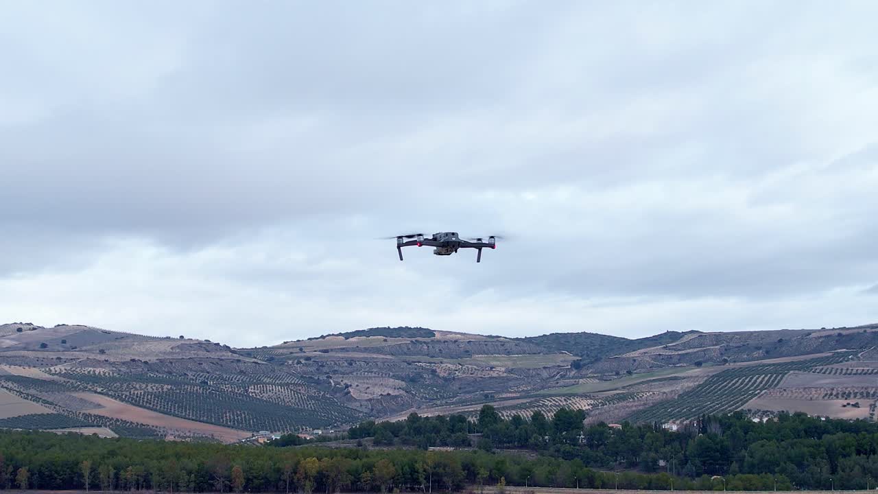 Rear view of drone in flight. Drone in flight with position lights and signal flashes. Close aerial view. Drone flying with cloudy sky in the background.