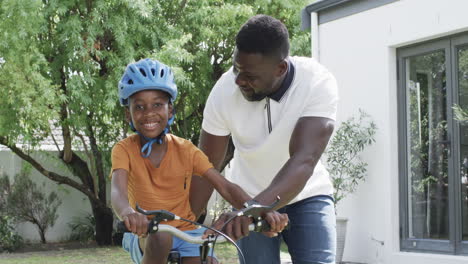 african american father teaches son to ride a bike outdoors