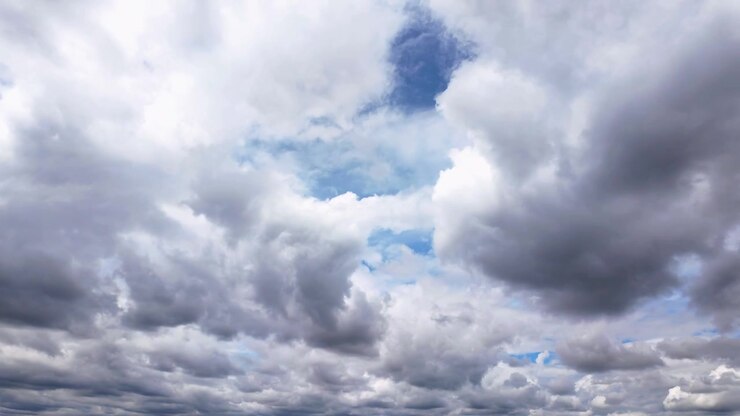 Dynamic timelapse of dark, dramatic clouds moving across a bright blue sky, creating an atmospheric and moody scene.