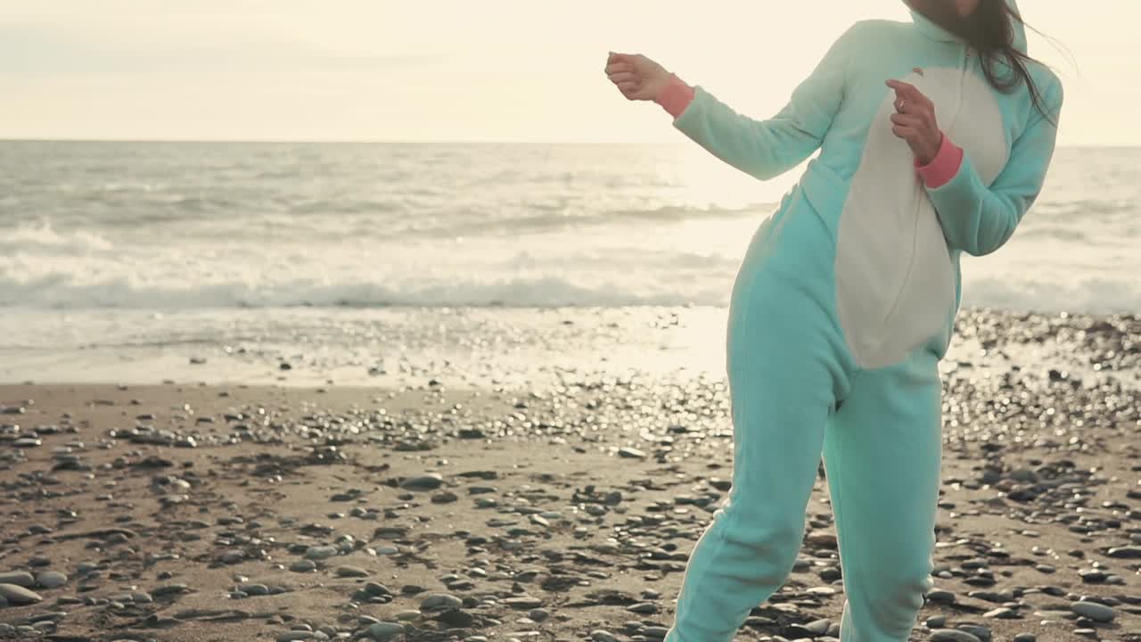 해가 지면 해변에서 춤을 추는 유니콘 잠옷을 입은 여자