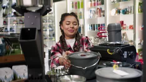mujer eligiendo olla de campamento en la tienda de deportes turísticos