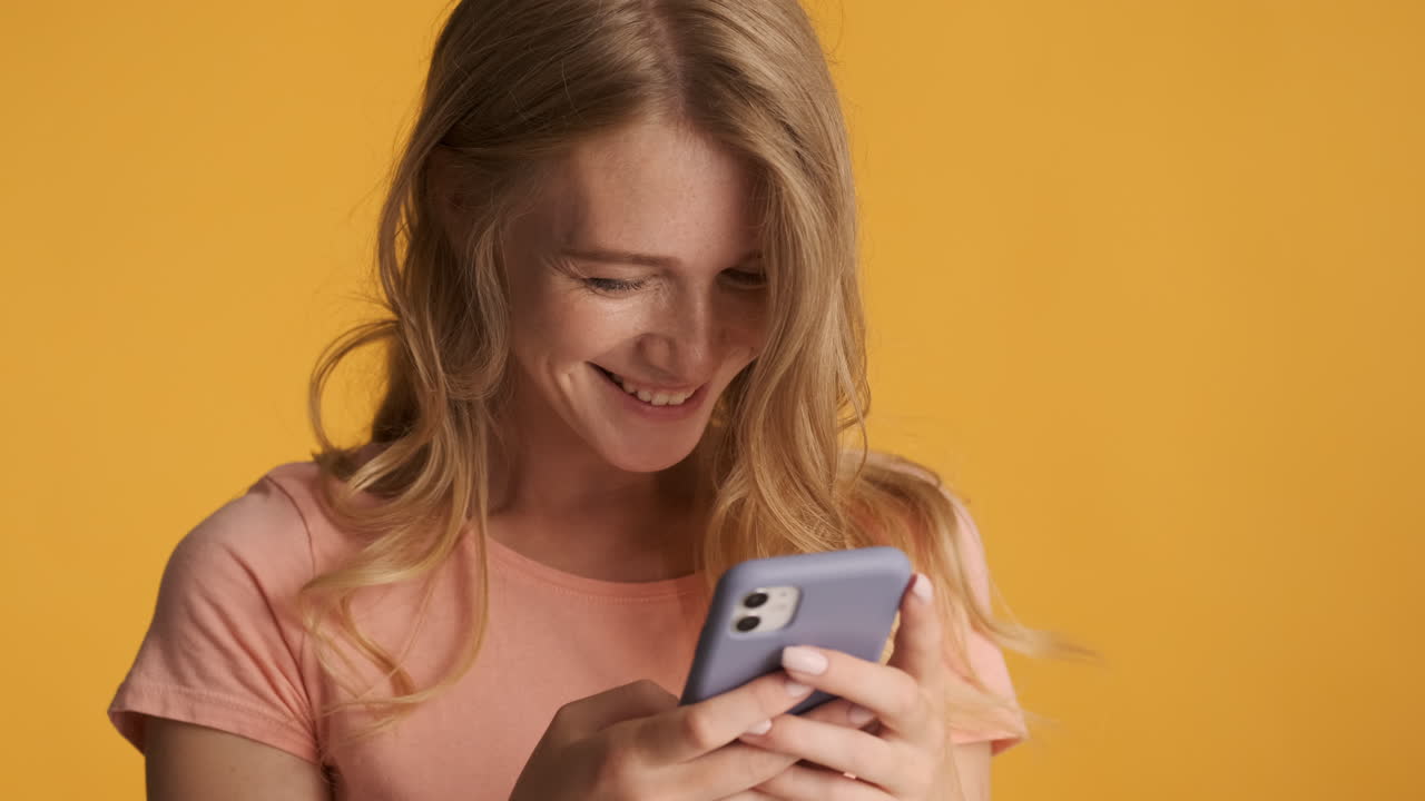 Caucasian woman using smartphone and smiling.