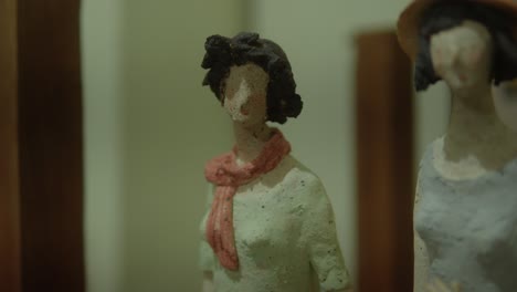 close-up of a faceless woman figurine wearing a scarf, highlighting the detailed features and textured surface