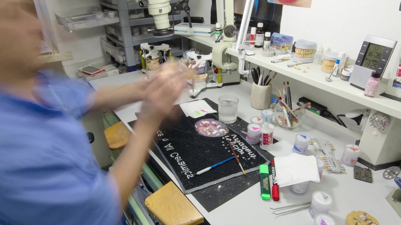 Tecnico dentale al lavoro con protesi dentale completa in metallo-ceramica superiore e inferiore, timelapse. Il dentista lavora con un pennello su un modello di mascella in un laboratorio clinico.