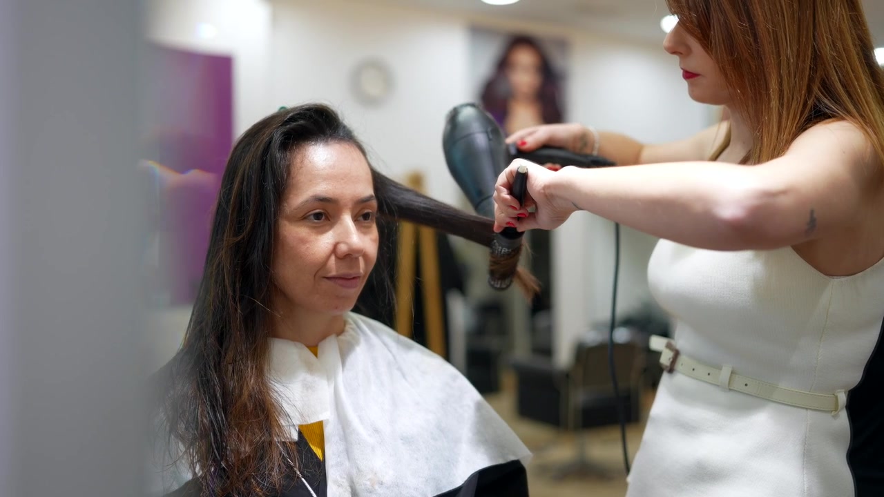 Estilista profesional secando el cabello de un cliente con secador en un salón