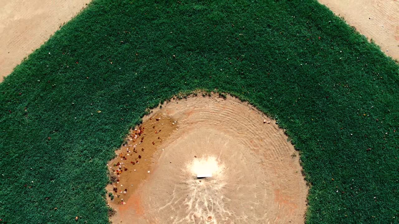Filmato drone 4K di un campo da baseball con i colori dell'autunno, grandi foglie rosse e arancioni sparse sul monte del lanciatore, che si alza nel cielo per mostrare il diamante sottostante