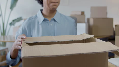 female office worker packing goods in cardboard parcel