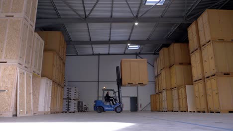 una carretilla elevadora guardando una de las grandes cajas de madera en su almacén de existencias