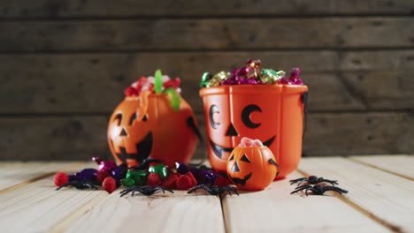 halloween pumpkin buckets full of halloween candies on wooden surface