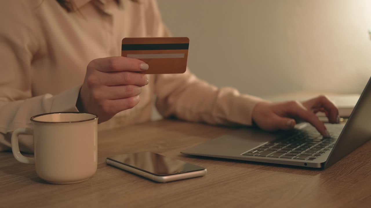 imágenes de cerca de una mujer sentada en la mesa de la oficina y usando tarjeta de crédito y computadora.