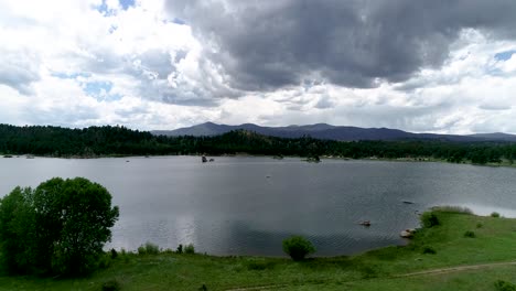 Tiro-De-Trípode-De-Drone-De-Un-Cielo-Oscuro-Rodando-Sobre-Un-Lago-Sereno-En-Las-Montañas-De-Colorado