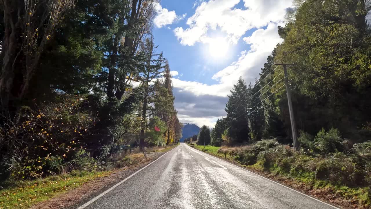 Veicolo percorre una strada di montagna rurale, attraversando foreste, campi e nuvole suggestive in pieno giorno