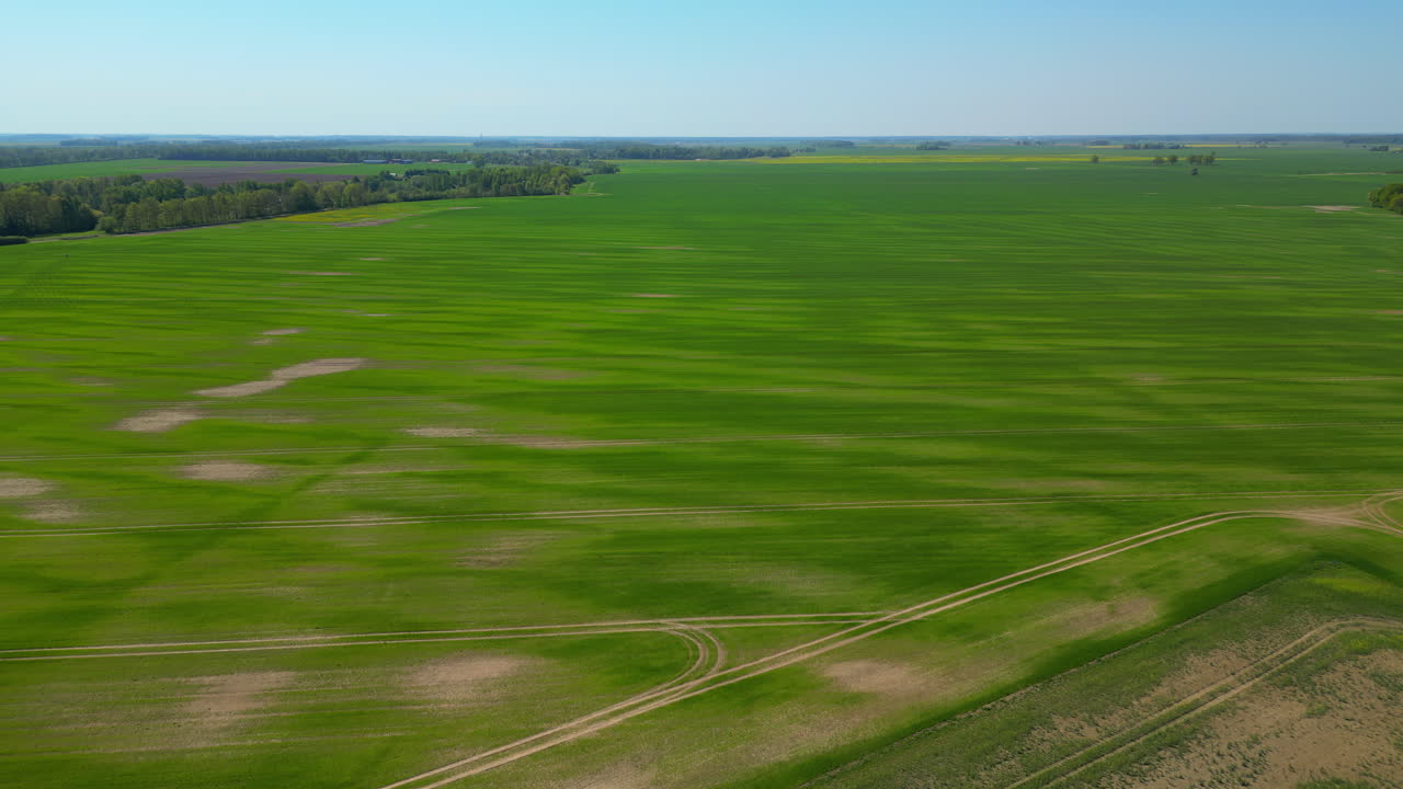 Drone flying over a farming community, open land and a forest treeline in the distance