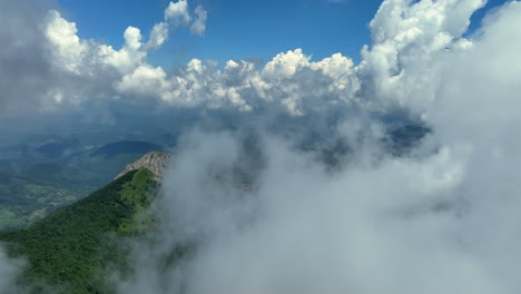 volando a través de nubes blancas y esponjosas por encima de los picos verdes de las montañas