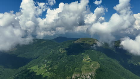 flying trough white fluffy clouds above green mountain peaks