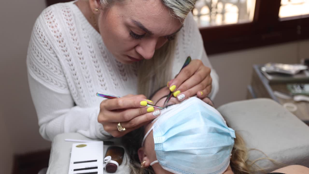 esteticista aplicando pestañas en la cara de la mujer
