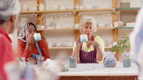 Happy-diverse-group-of-potters-having-break-and-discussing-in-pottery-studio,-slow-motion