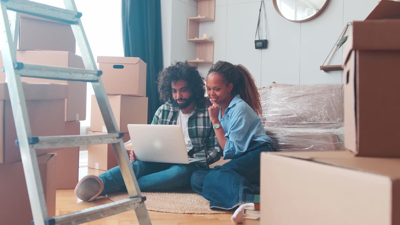 Young multicultural couple man and woman with laptop after moving to new house