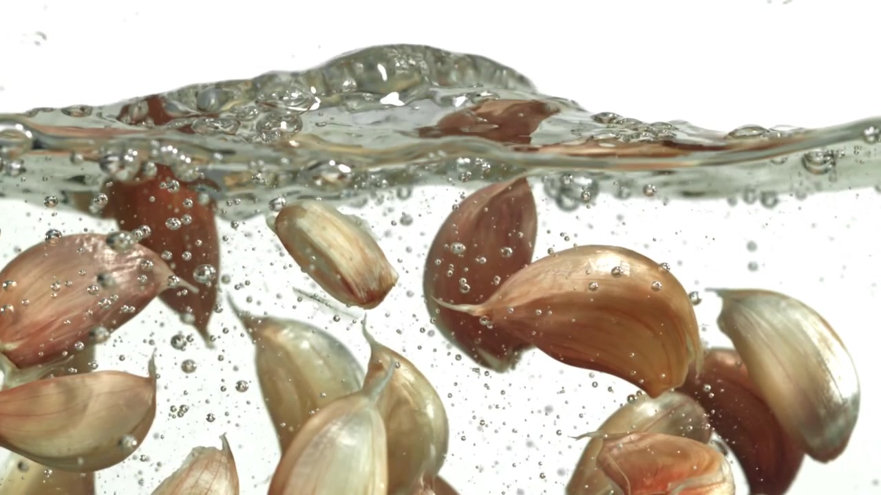 Fresh Garlic Cloves Submerged in Water with Rising Bubbles