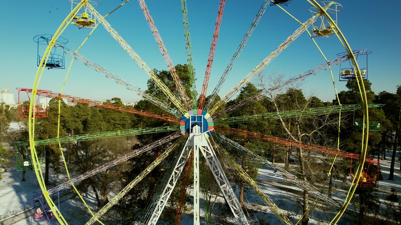 заброшенное аттракционное колесо в зимнем городском парке.