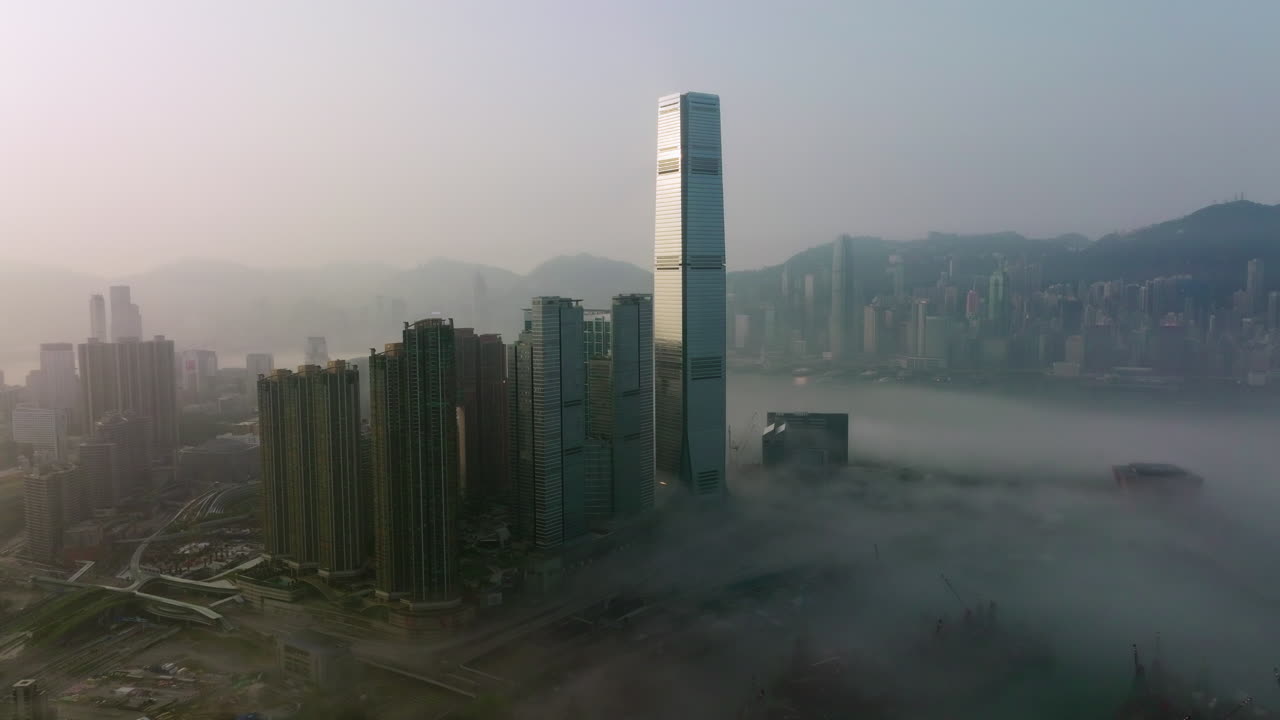 Tomada aérea grande angular com tracking lento para a direita de edifícios altos de West Kowloon cobertos por nevoeiro, Ilha de Hong Kong