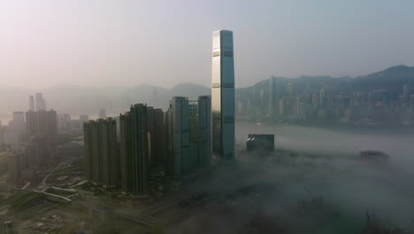 wide-angle-slow-tracking-right-aerial-shot-of-fog-covered-West-Kowloon-high-rise-buildings,-Hong-Kong-Island