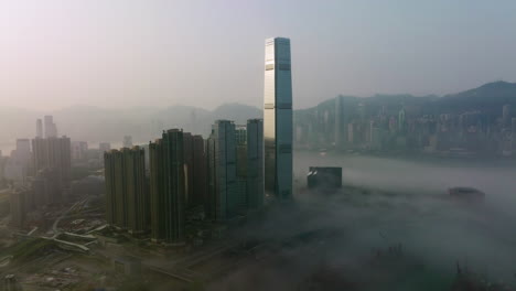 wide angle slow tracking right aerial shot of fog covered west kowloon high-rise buildings, hong kong island