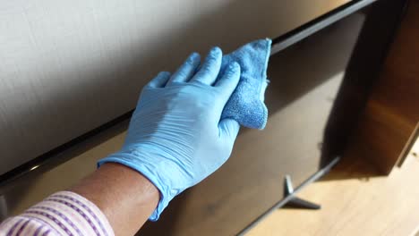 cleaning a flat screen tv with blue gloves