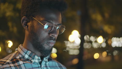 african american  man using smartphone outdoors in evening