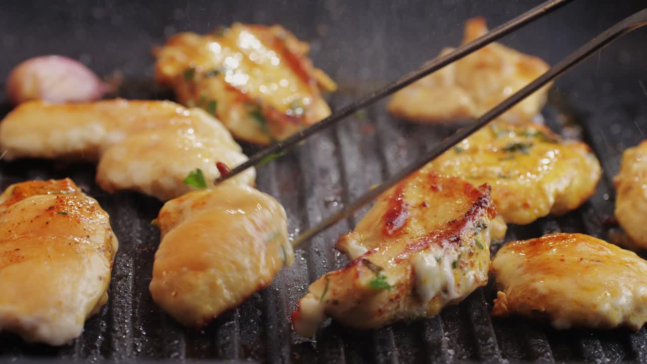 Cooking raw chicken meat in yellow turmeric spice with garlic and greens on grill close-up. Fry chicken slice on frying.pan Grilled chicken, duck, turkey kebab with vegetables.