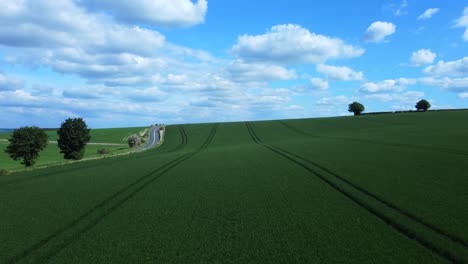Drone-flying-over-beautiful-green-harvested-field-in-Wiltshire-countryside,-England