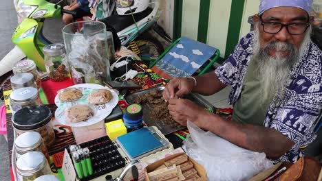 elderly craftsman creates colorful beadwork with skill