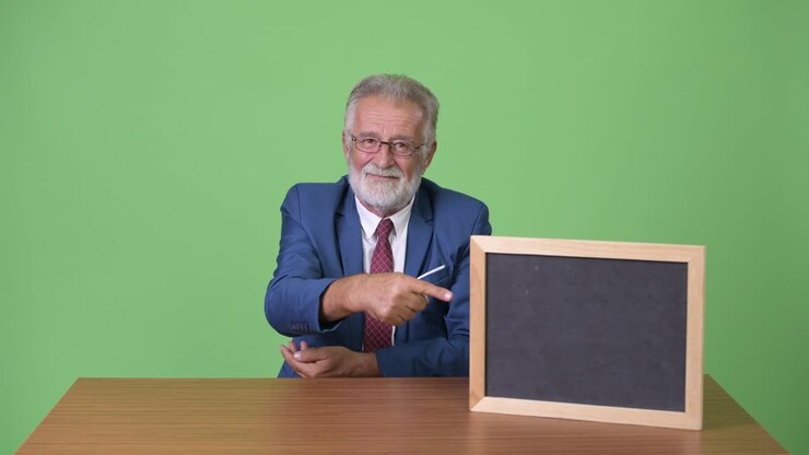 Handsome senior bearded businessman against green background