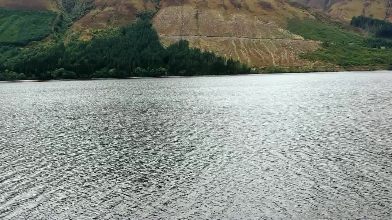 산악 스코틀랜드 고원의 외딴 호수 위의 낮은 공중 비행