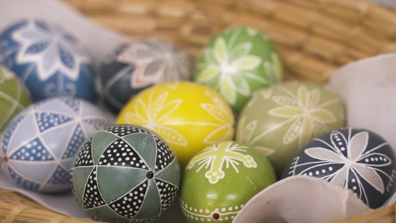 Basket of pastel-colored Easter eggs with traditional folk patterns in soft spring hues