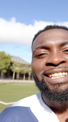 vertical video: smiling man enjoying sunny day outdoors on sports field, feeling happy