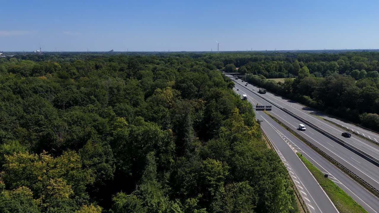 American highway near dense forest trees in summer. Driving cars on trucks on interstate expressway. Aerial lateral wide shot. Scenic Suburb district of u.s