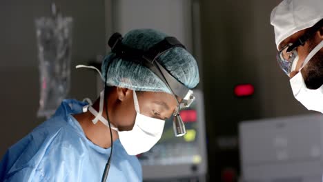 african american male and female surgeons wearing surgical gowns, operating on patient, slow motion