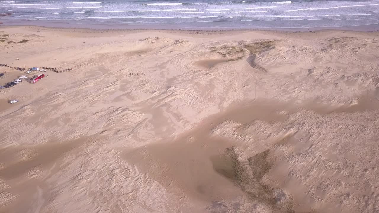 acercamiento aéreo a una amplia playa de arena con olas blancas y dunas de arena en la playa de stockton