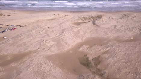 Aerial-zoom-in-to-a-wide-sandy-beach-with-white-waves-and-sand-dunes-at-Stockton-Beach