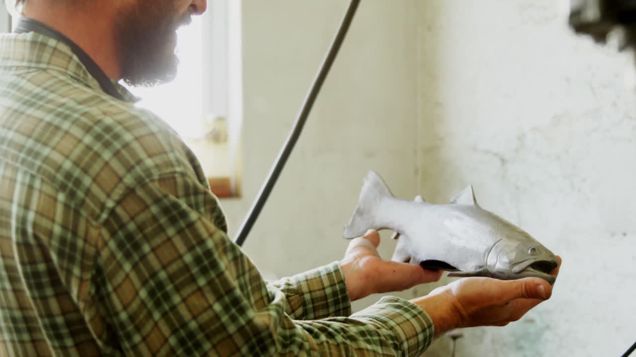 Craftsman examining fish sculpture 4k