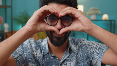 Happy-indian-man-guy-makes-symbol-of-love-showing-heart-sign-to-camera-express-romantic-feelings