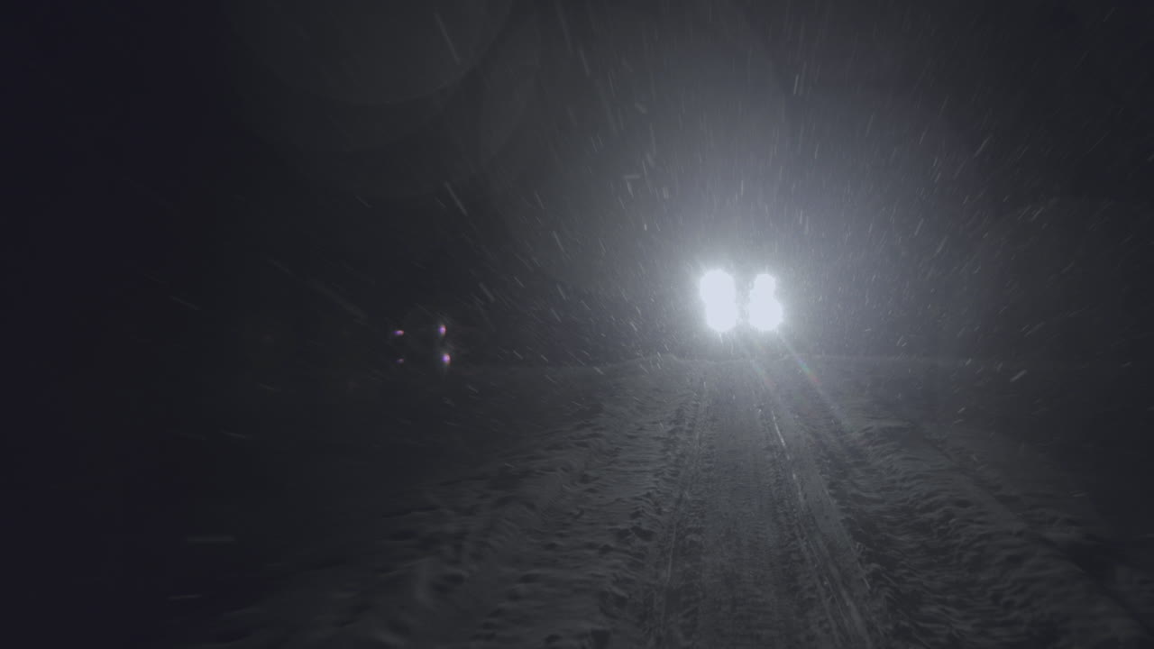 Half-track driving in the night in Jotunheimen in Norway. The half-track has skies in front. Its night and the snow are falling. Filmed on a gimbal in 4k.