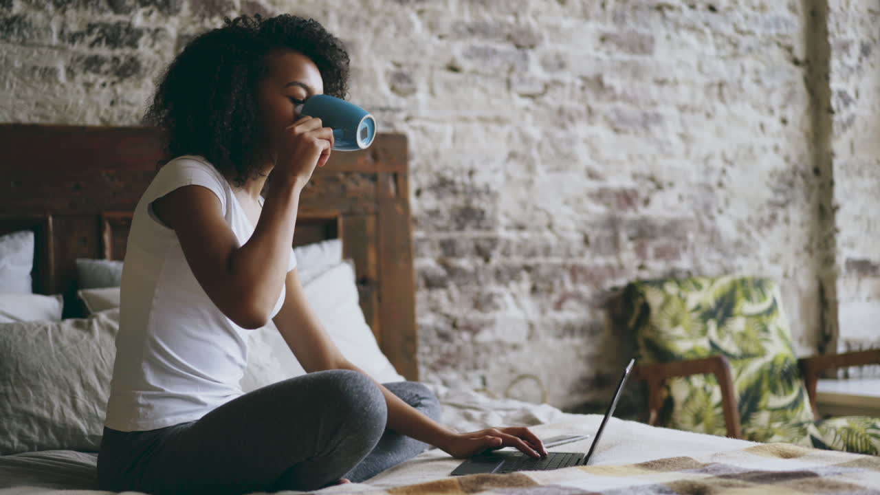 mujer joven trabajando en una computadora portátil en el dormitorio