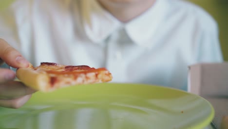 un niño muerde una rebanada de pizza con salchicha de un plano de cerca